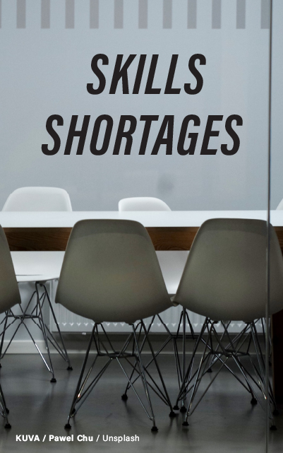 A grayscale image of empty modern chairs set up in a row, indicating a vacant or unattended setting, with the prominent text "Skills Shortages" on a semi-transparent background. Photo credited to Pawel Chu on Unsplash.